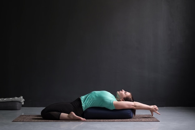 Linda garota atlética fazendo yoga supta virasana asana usando travesseiro