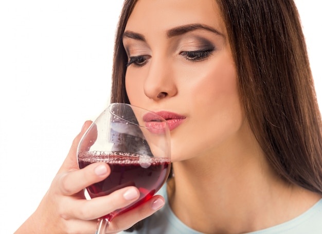 Linda garota bebe vinho tinto de vidro.