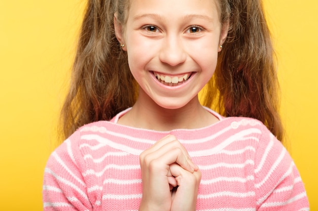 Linda garota bonita sorridente. pequeno retrato de criança despreocupada em amarelo. emoção e expressão facial.
