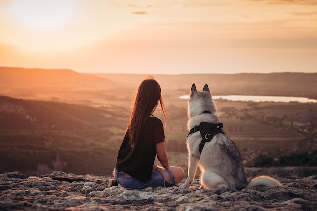 Linda garota brinca com cachorro ao pôr do sol