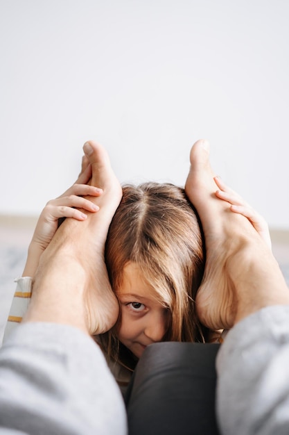 Linda garota brincando com os pés do pai escondidos olhando para ele