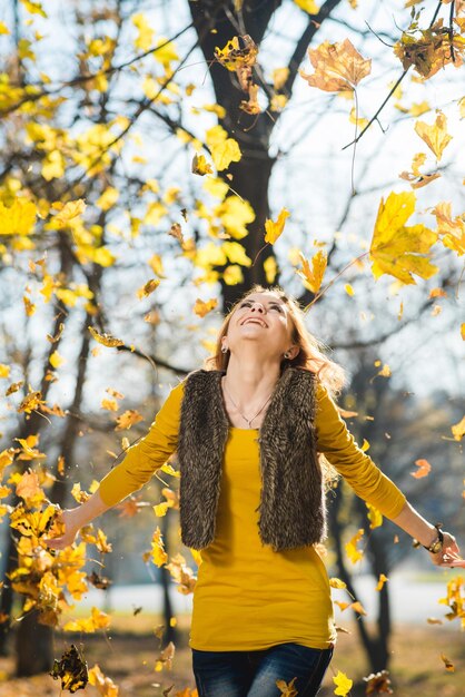 Linda garota caminha no parque outono com folhas amarelas caídas