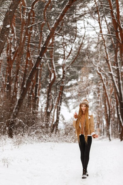 Linda garota caminhando pela floresta de neve de inverno