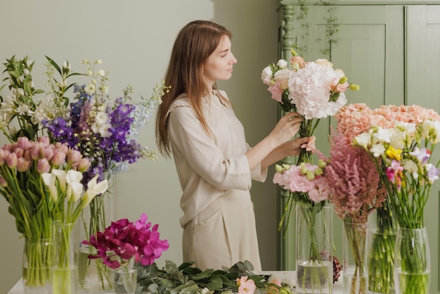 Linda garota coleta um buquê de flores em uma loja de flores