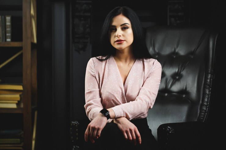 Linda garota com blusa clara na cadeira de couro preta