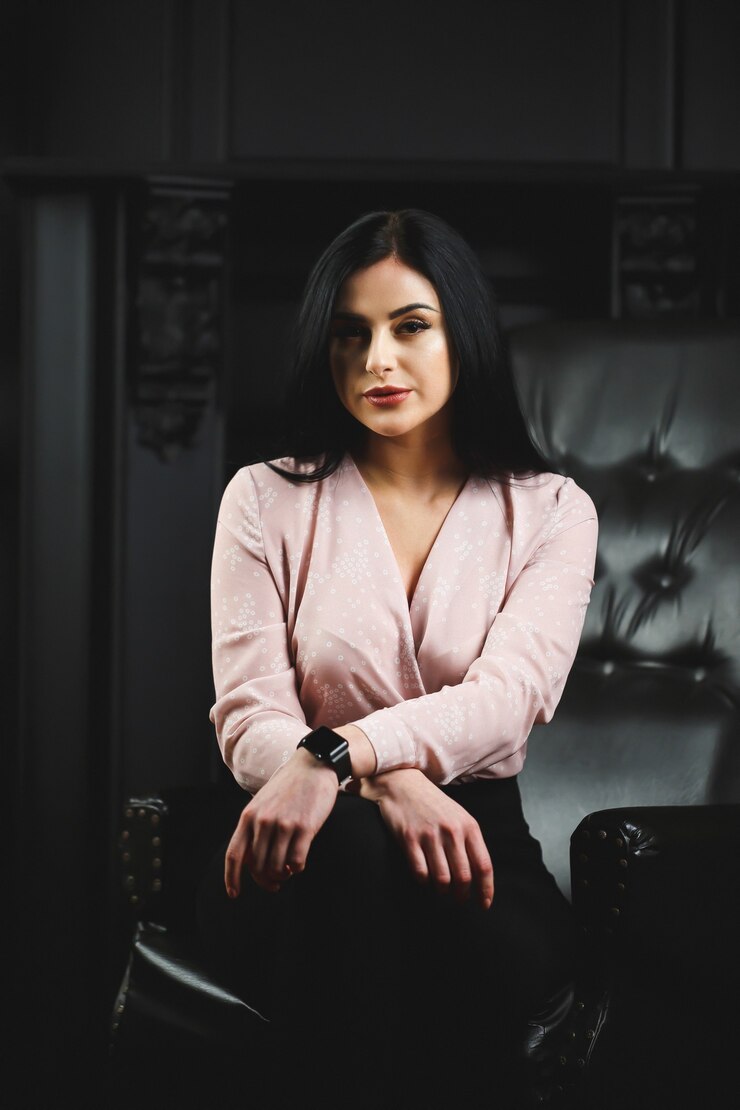 Linda garota com blusa clara na cadeira de couro preta