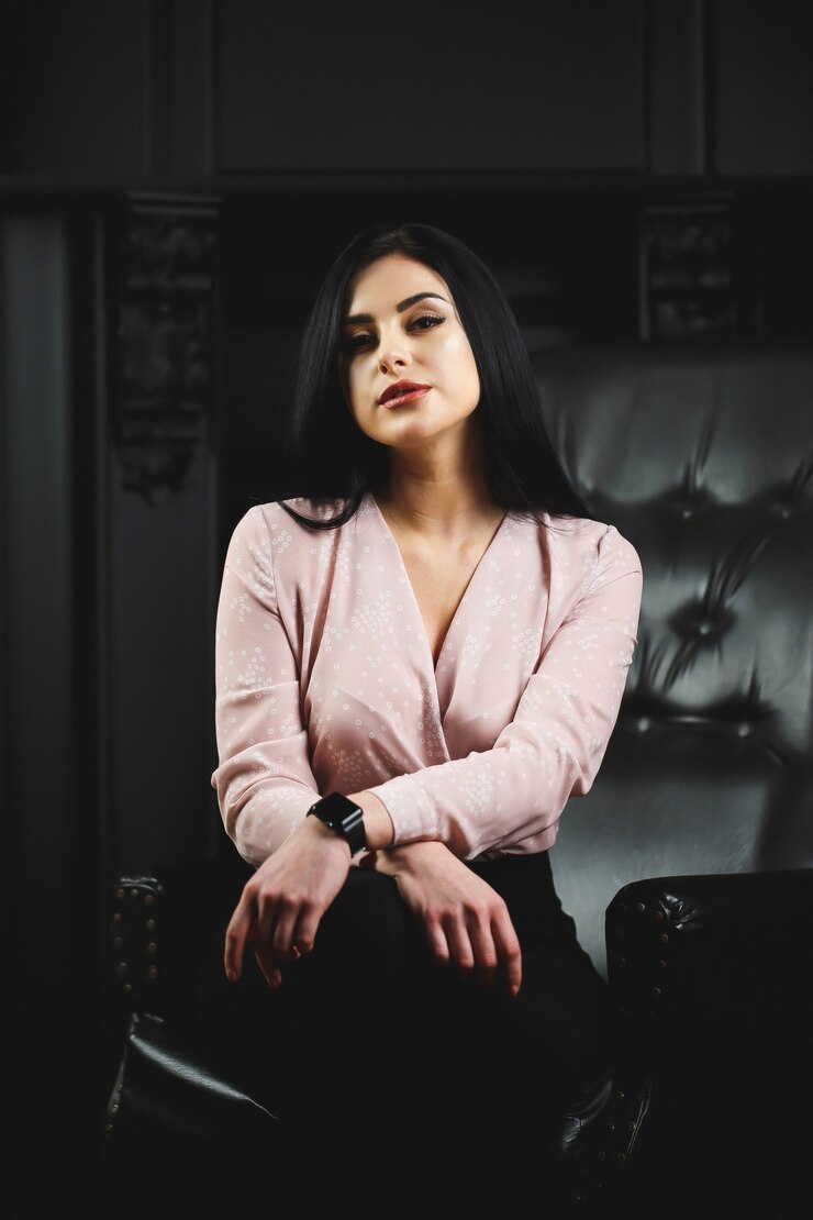 Linda garota com blusa clara na cadeira de couro preta