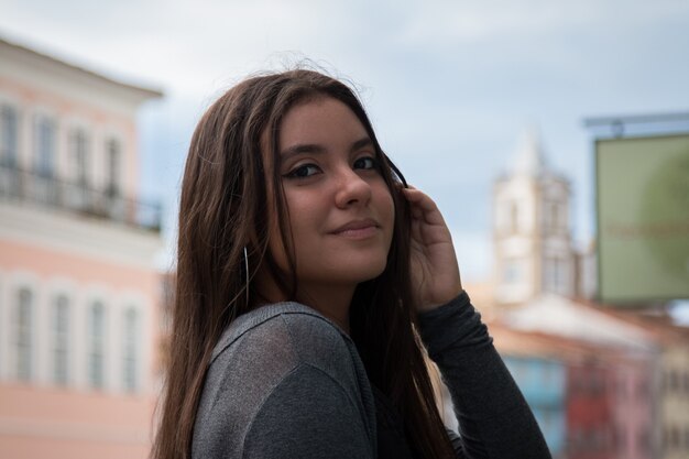 Linda garota com cabelo castanho escuro pousando na rua.