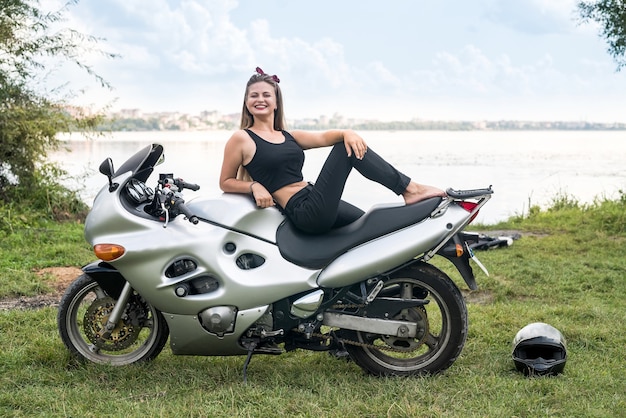 Linda garota com cabelo comprido posando em uma motocicleta