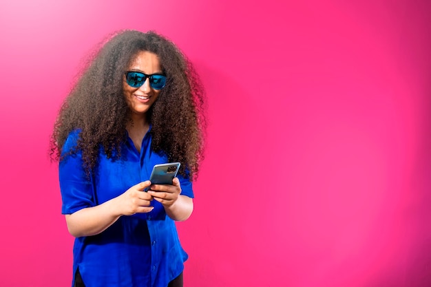 Linda garota com cabelo estilo afro sorrindo com óculos azuis no espaço de cópia fundo rosa Feminilidade