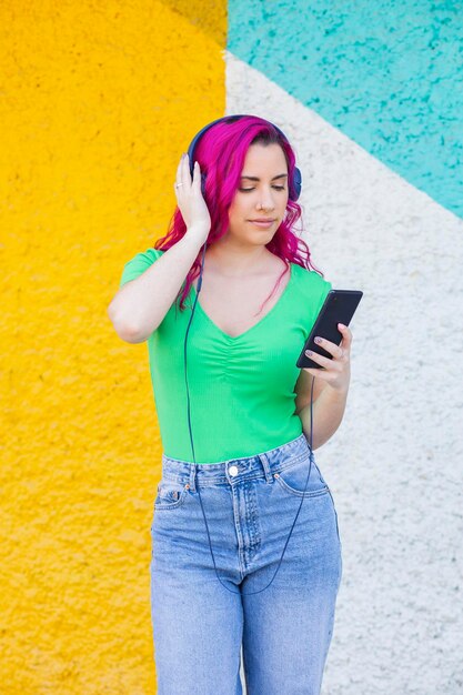 Linda garota com cabelo rosa ouvindo música em fones de ouvido estilo de rua colorida ba