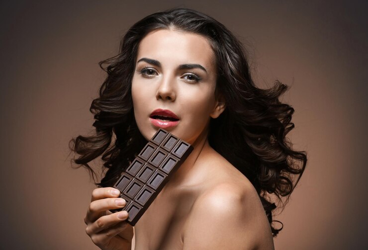 Foto linda garota com chocolate no fundo marrom