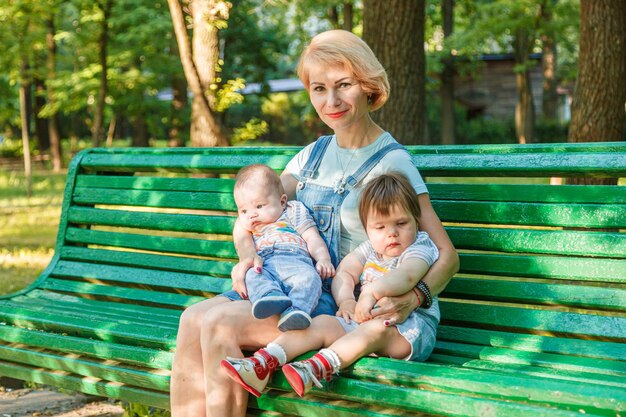 Linda garota com crianças se senta em um banco no parque