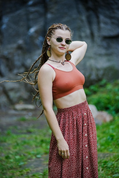 Linda garota com dreadlocks vestidos de estilo hippie ao ar livre