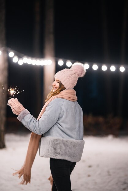 Foto linda garota com estrelinhas nas mãos feliz inverno na floresta luzes festivas de guirlanda