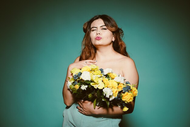 Linda garota com flores sobre estúdio ciano