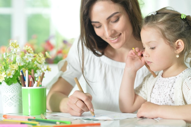 linda garota com mãe desenhando na mesa