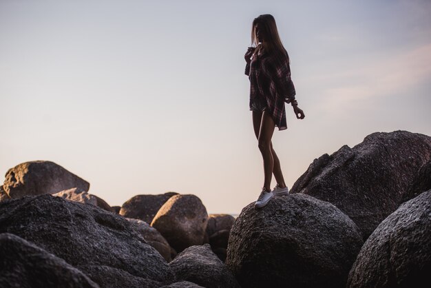 linda garota com óculos de sol andando nas pedras