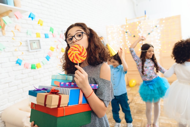 Foto linda garota com óculos e bando de presentes nas mãos.