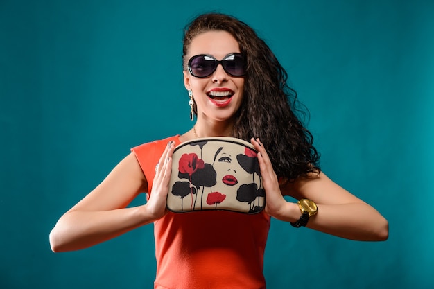 Linda garota com óculos escuros e bolsa de mão nas mãos