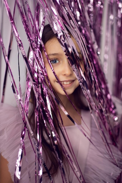 Linda garota com olhos grandes em um vestido rosa em contraste com o fundo de enfeites de ano novo