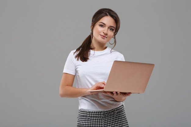 Linda garota com roupas casuais trabalhando em um laptop
