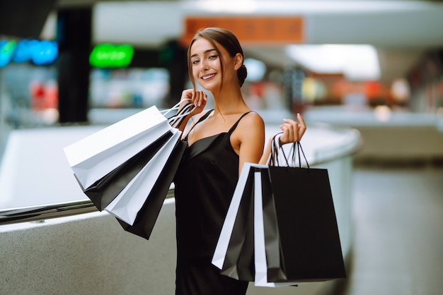 Linda garota com sacolas de compras, olhando para a câmera e sorrindo enquanto fazia compras no shopping