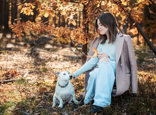 Linda garota com seu cachorro na floresta. Floresta de outono.