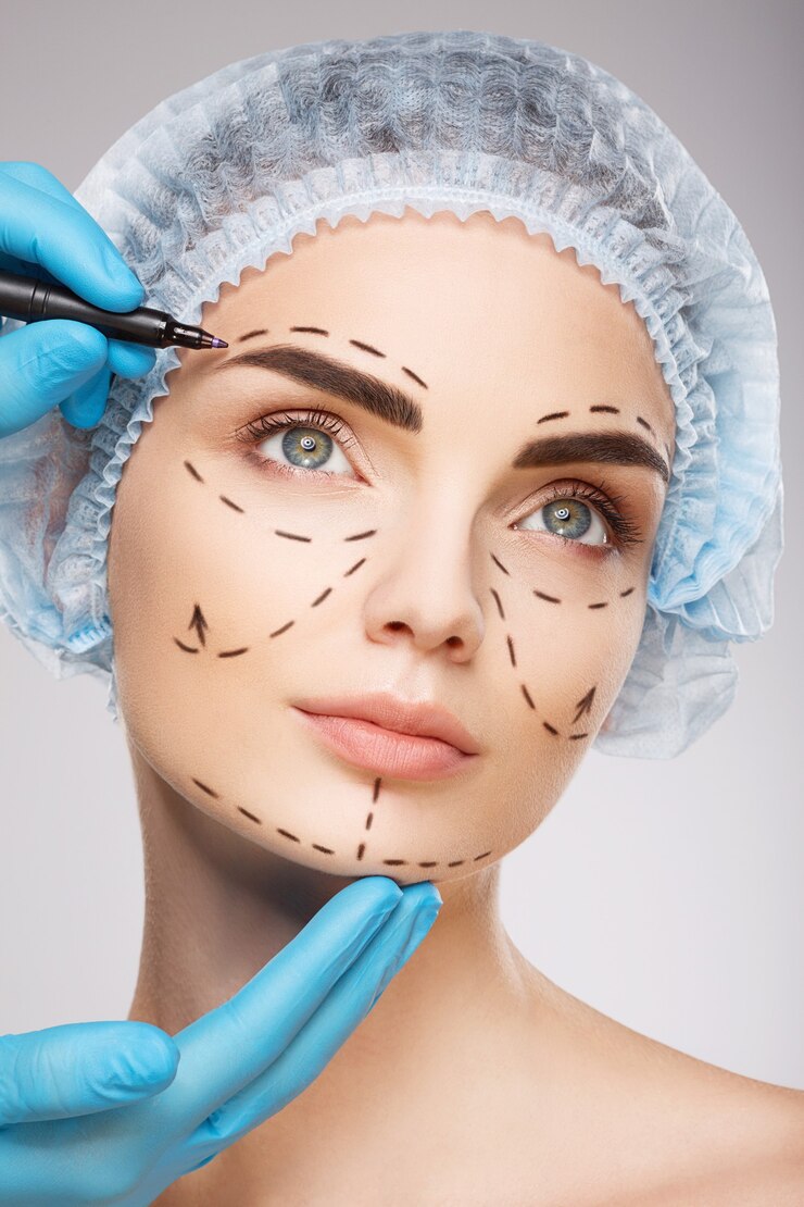 Foto linda garota com sobrancelhas escuras, usando chapéu azul médico na parede, as mãos do médico usando luvas azuis desenhando linhas de perfuração no rosto, conceito de cirurgia plástica.