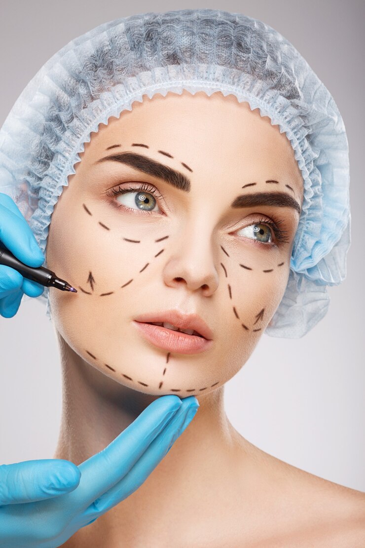 Foto linda garota com sobrancelhas escuras, usando chapéu azul médico no fundo do estúdio, as mãos do médico usando luvas azuis desenhando linhas de perfuração no rosto.