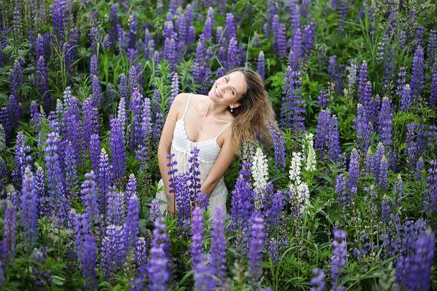 Linda garota com um buquê de flores azuis na natureza no verão