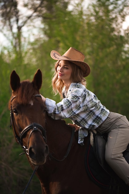 Linda garota com um chapéu, andando a cavalo no campo