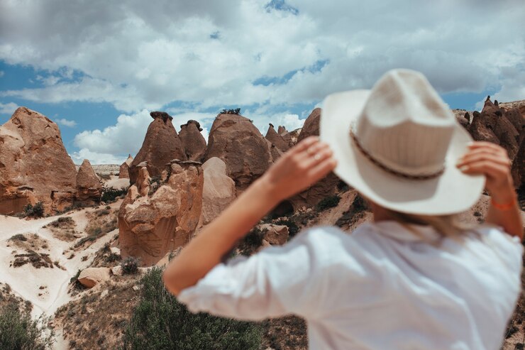Foto linda garota com um chapéu olha para a paisagem da capadócia