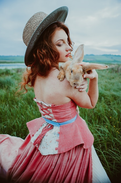 linda garota com um coelho ao ar livre em dia de verão