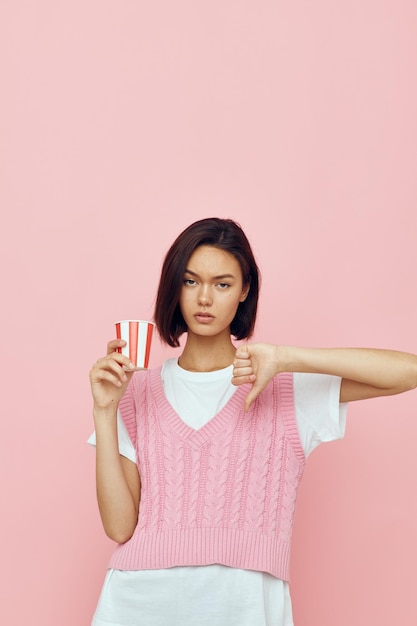 Linda garota com um copo na mão estilo verão camiseta rosa isolado fundo