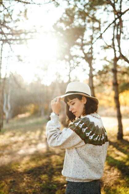 Foto linda garota com um lindo sorriso ao pôr do sol na floresta a garota está vestida com um chapéu