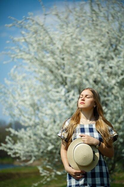 Linda garota com um vestido andando na floresta de primavera, onde as árvores florescem