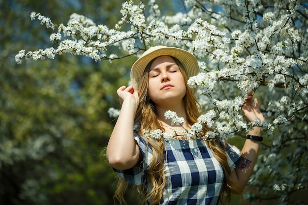 Linda garota com um vestido andando na floresta de primavera, onde as árvores florescem