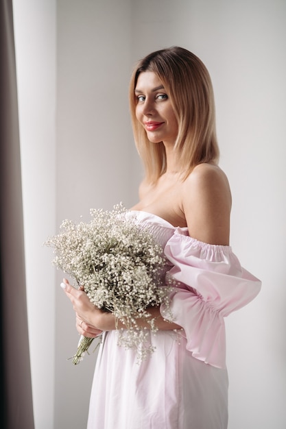 Linda garota com um vestido branco segurando um boquete de flores brancas