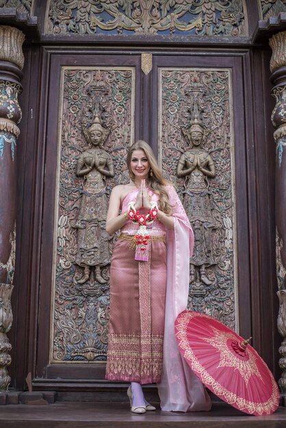 Linda garota com um vestido brilhante nacional tailandês com maquiagem oriental viaja para a tailândia