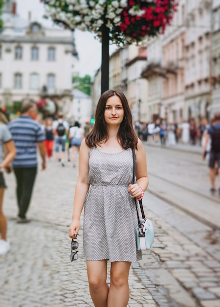 Linda garota com um vestido de verão caminha pela cidade