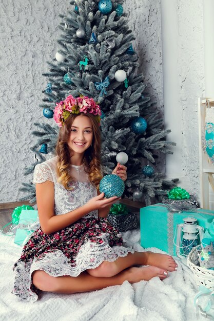 Linda garota com um vestido perto da árvore de Natal