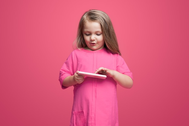 Linda garota com um vestido vermelho brincando com um tablet na parede tocando a tela e sorrindo