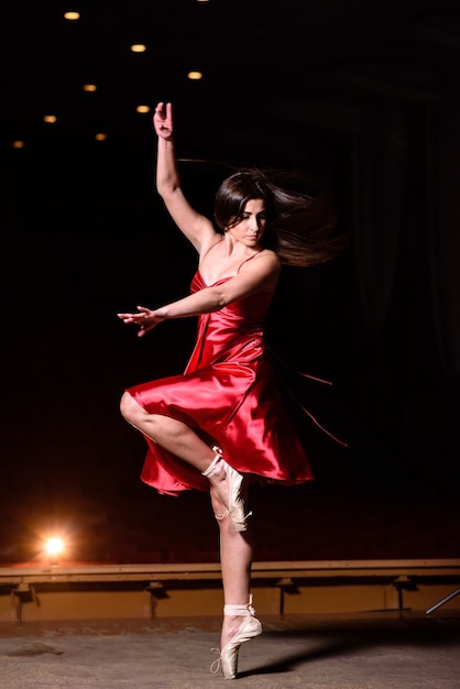 Linda garota com um vestido vermelho dançando no palco.