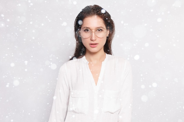 Linda garota com uma camiseta branca em branco usando óculos, parede vazia, retrato de estúdio