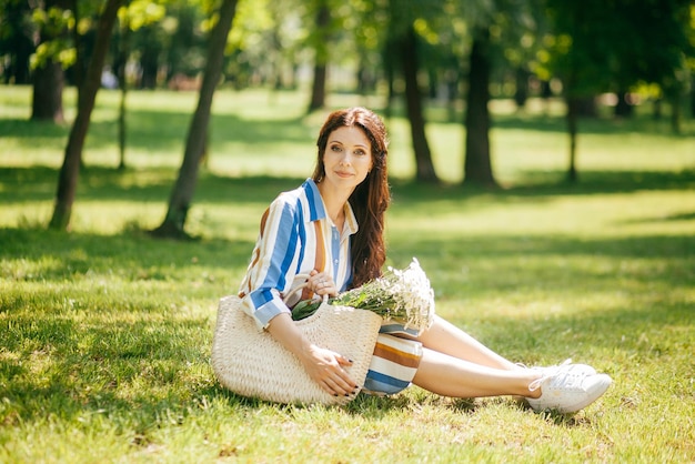Linda garota com uma cesta de flores brancas no parque