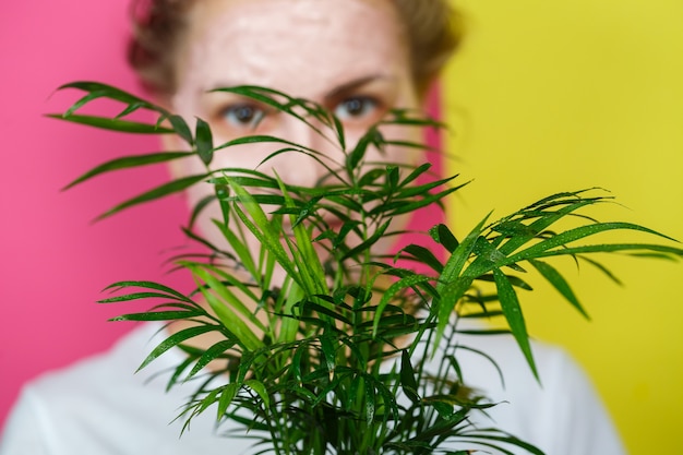 Linda garota com uma máscara refrescante no rosto. Segurando uma palma decorativa nas mãos. Beleza e pele saudável