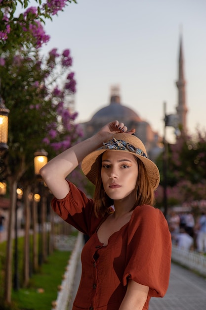 Linda garota com vestido laranja posando com a Mesquita Sultan Ahmet durante o pôr do sol de Istambul