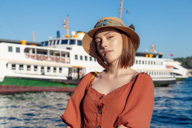 Linda garota com vestido laranja posando com o Ferry em Istambul