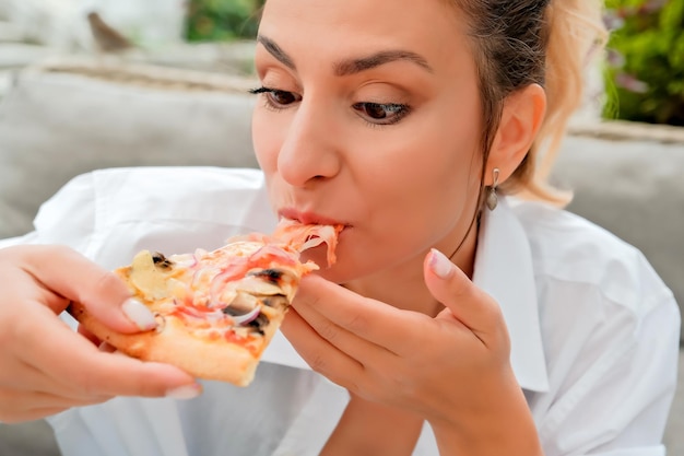 Linda garota come pizza em um café de rua garota mostra emoções diferentes